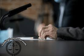 Close-up view of a lawyer’s hands signing legal documents at a desk with a microphone, symbolizing leading lawyer services, strong defense, and strategic legal solutions.